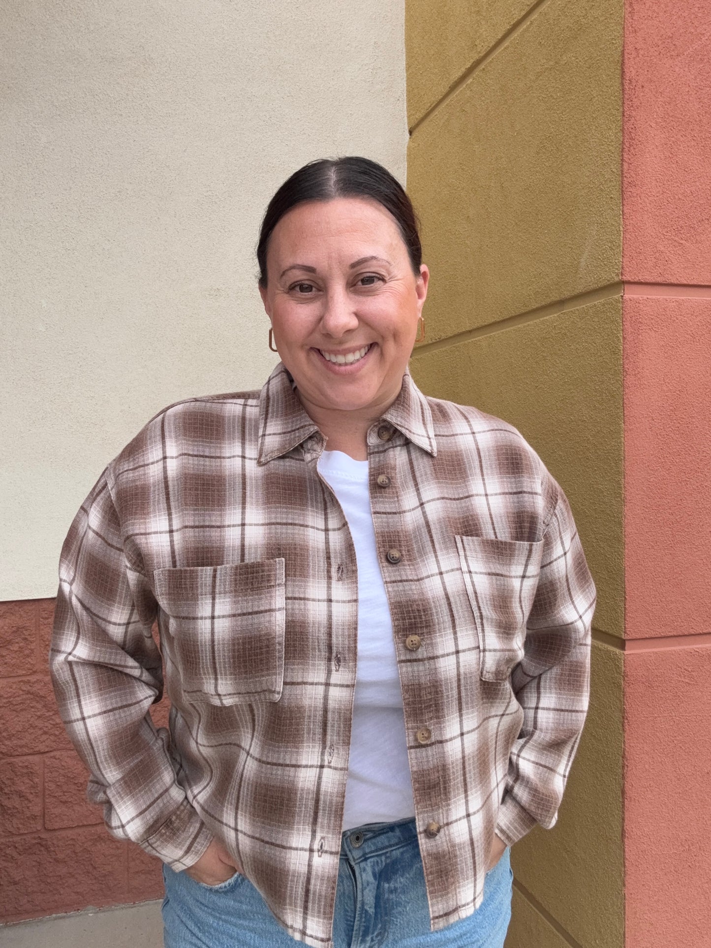 Person wearing a plaid shirt and jeans standing on a checkered floor.