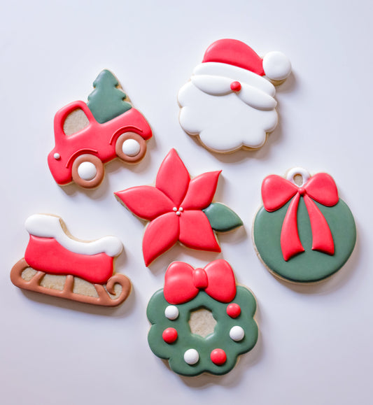 Decorative cookies shaped like a Christmas tree, Santa Claus, poinsettia, gift, and wreath on a white background.