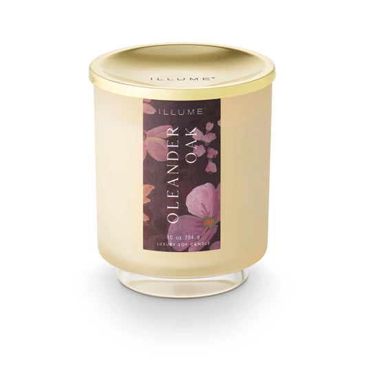 Candle with a gold lid and floral label on a white background