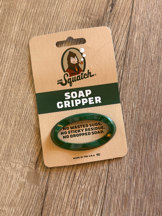 Green soap gripper on a wooden card with branding on a wooden surface