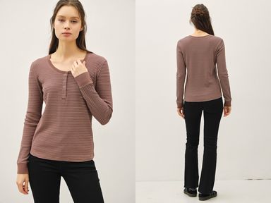 Woman wearing a brown long-sleeve top and black pants on a white background