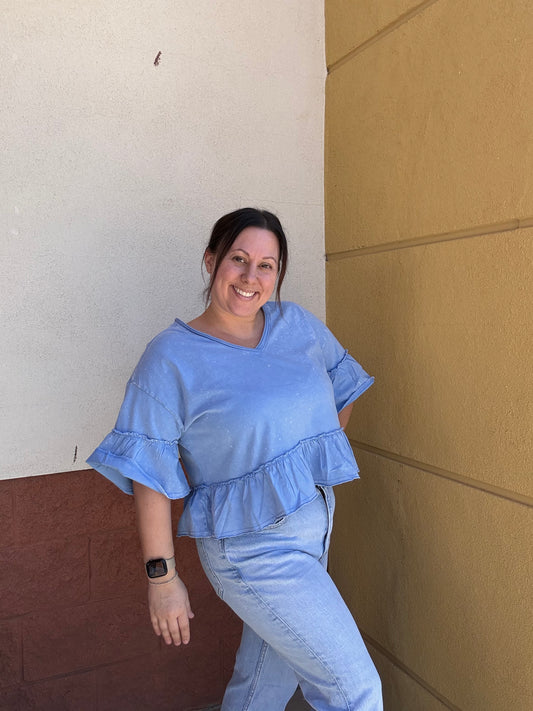 Blue ruffle top on model wearing jeans 