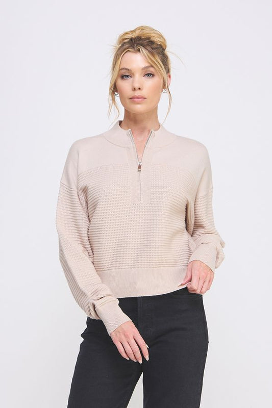 Woman wearing a beige long-sleeve shirt with a quarter zip on a white background