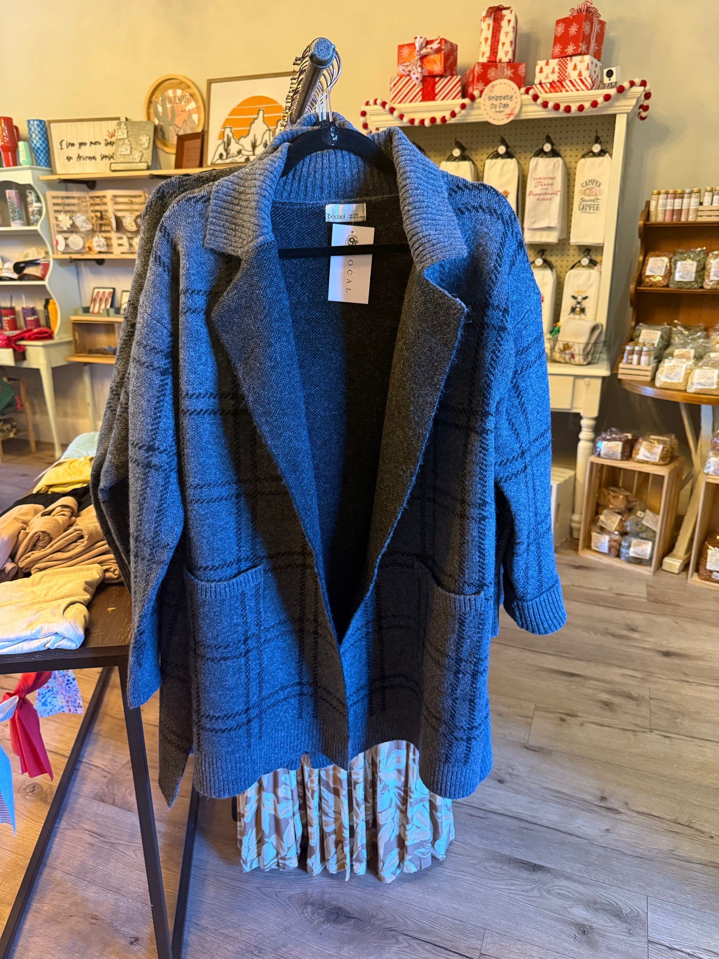 Blue cardigan on a hanger in a store setting with various products in the background.
