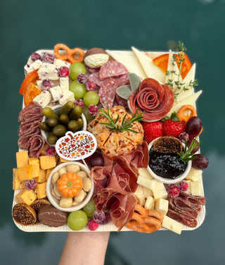 Assorted charcuterie board with meats, cheeses, fruits, and vegetables on a white tray.