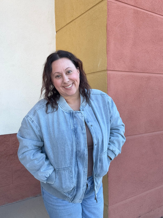 Person wearing a light blue jacket and jeans standing on a multicolored floor.