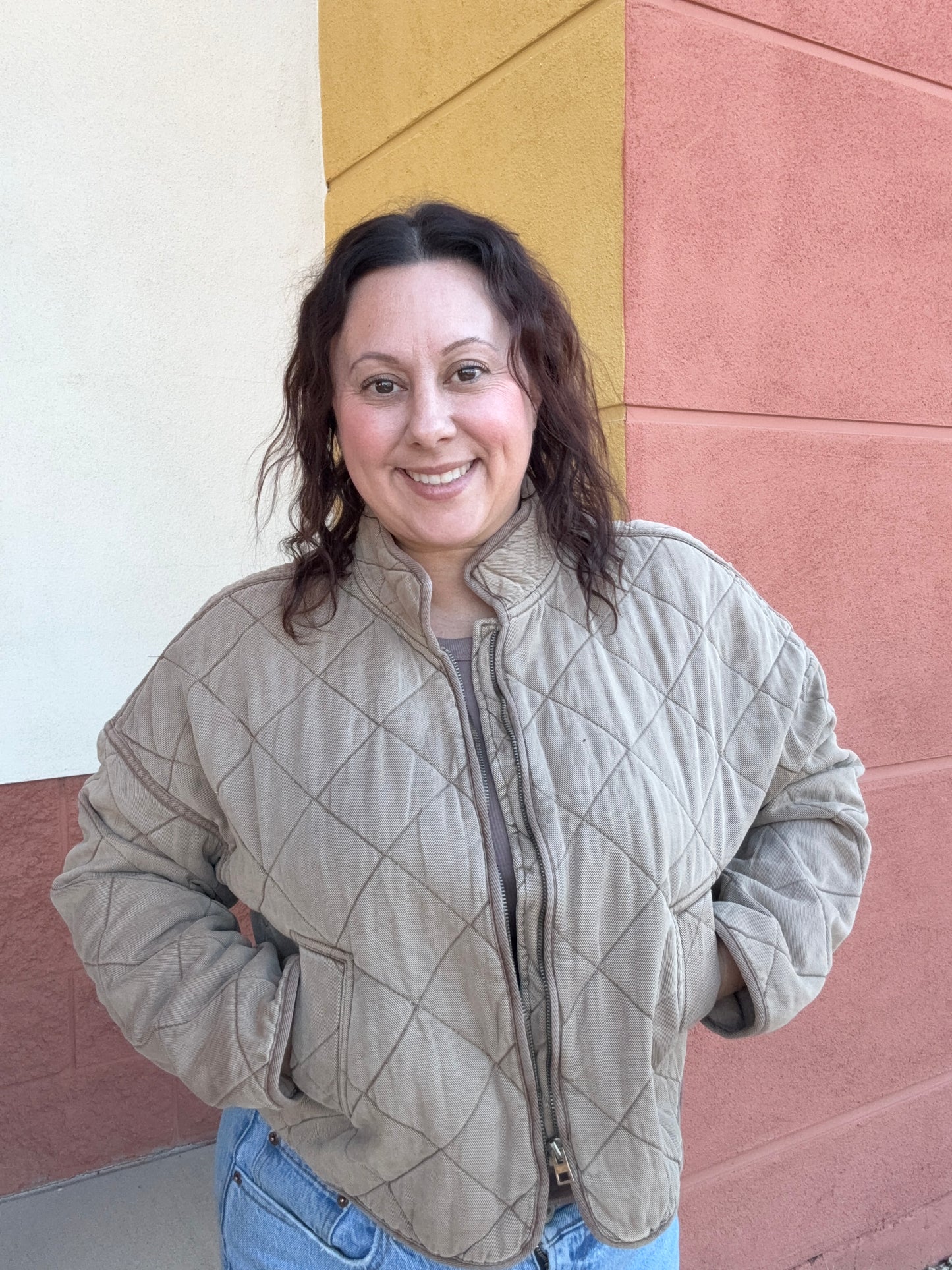 Person wearing a quilted jacket standing on a colorful geometric-patterned floor.