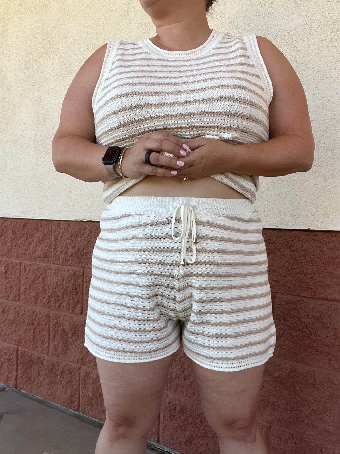 Person wearing a matching striped tank top and shorts set against a textured wall.