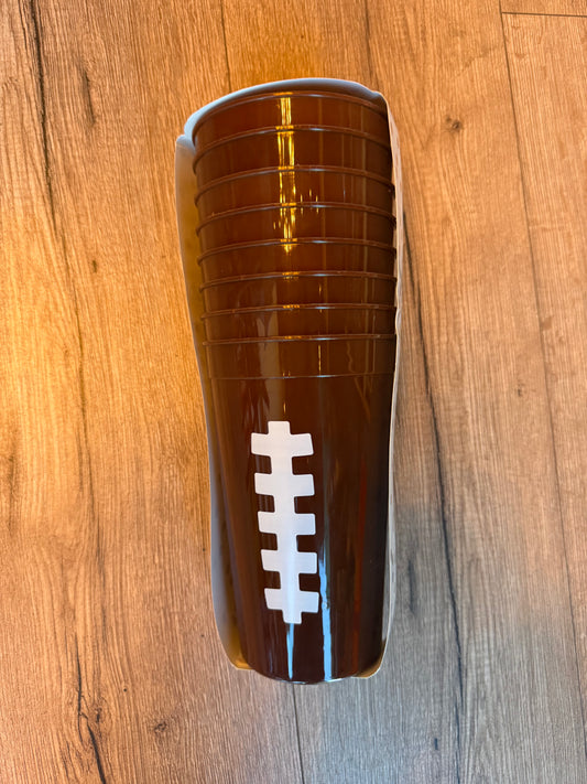 A stack of translucent brown plastic cups with a white football laces graphic, resting on a wooden floor.