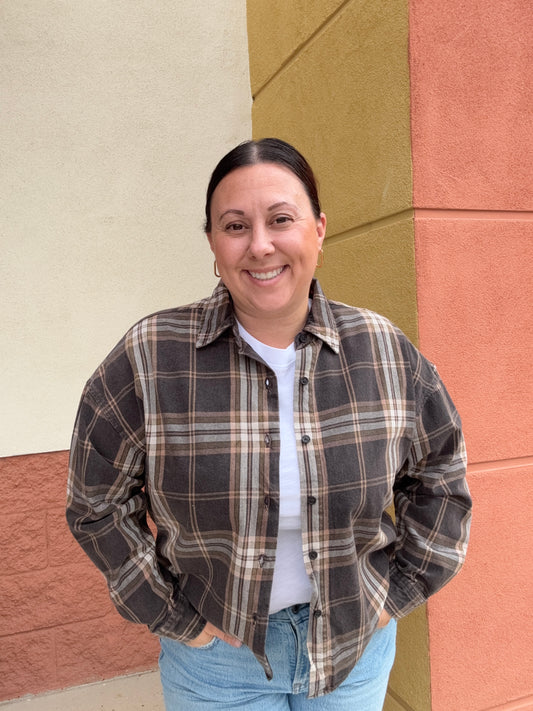 Person wearing a plaid jacket and jeans standing on a multicolored floor.