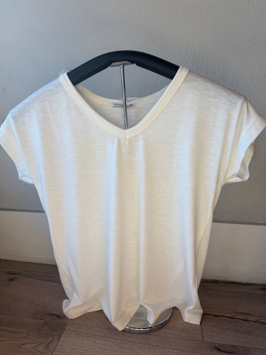A white short-sleeve V-neck t-shirt displayed on a black hanger against a light gray wall and wood floor.