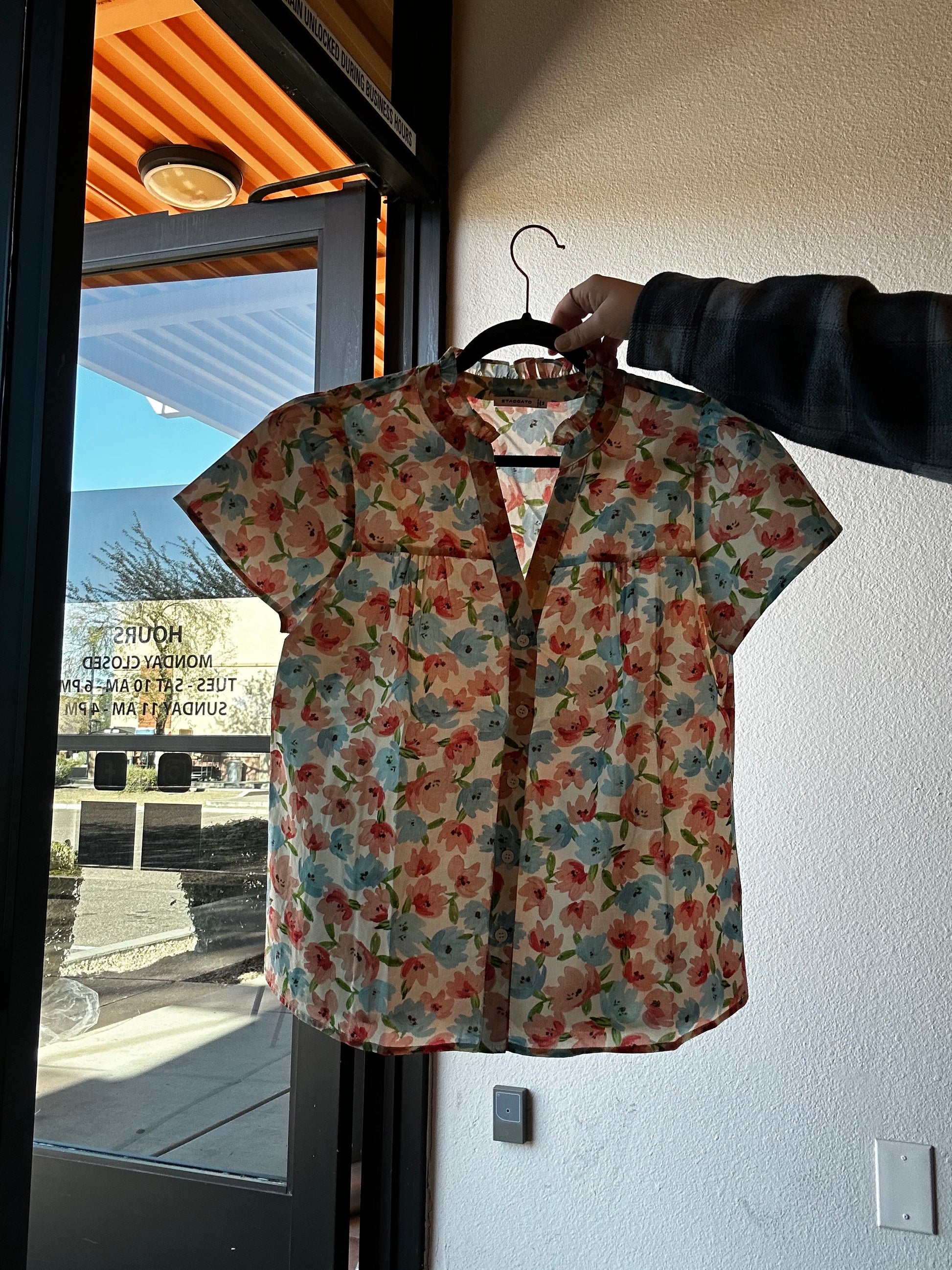 Floral-patterned garment on a hanger with a reflective surface below