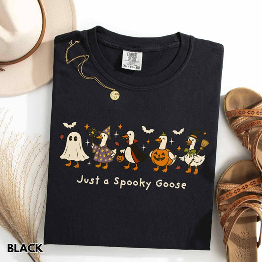 Black t-shirt with Halloween-themed design of geese and text 'Just a Spooky Goose' on a white surface.