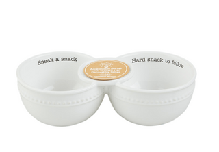 A white ceramic two-bowl snack tray with black printed text reading 'Sneak a snack' on the left bowl and 'Hard snack to follow' on the right bowl, connected by a small round gold center piece, on a white background.