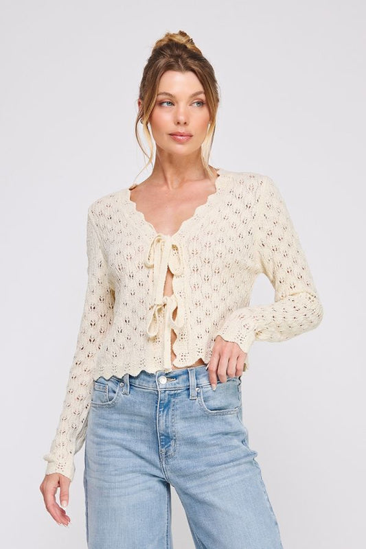 Woman wearing a cream lace top and light blue jeans on a white background